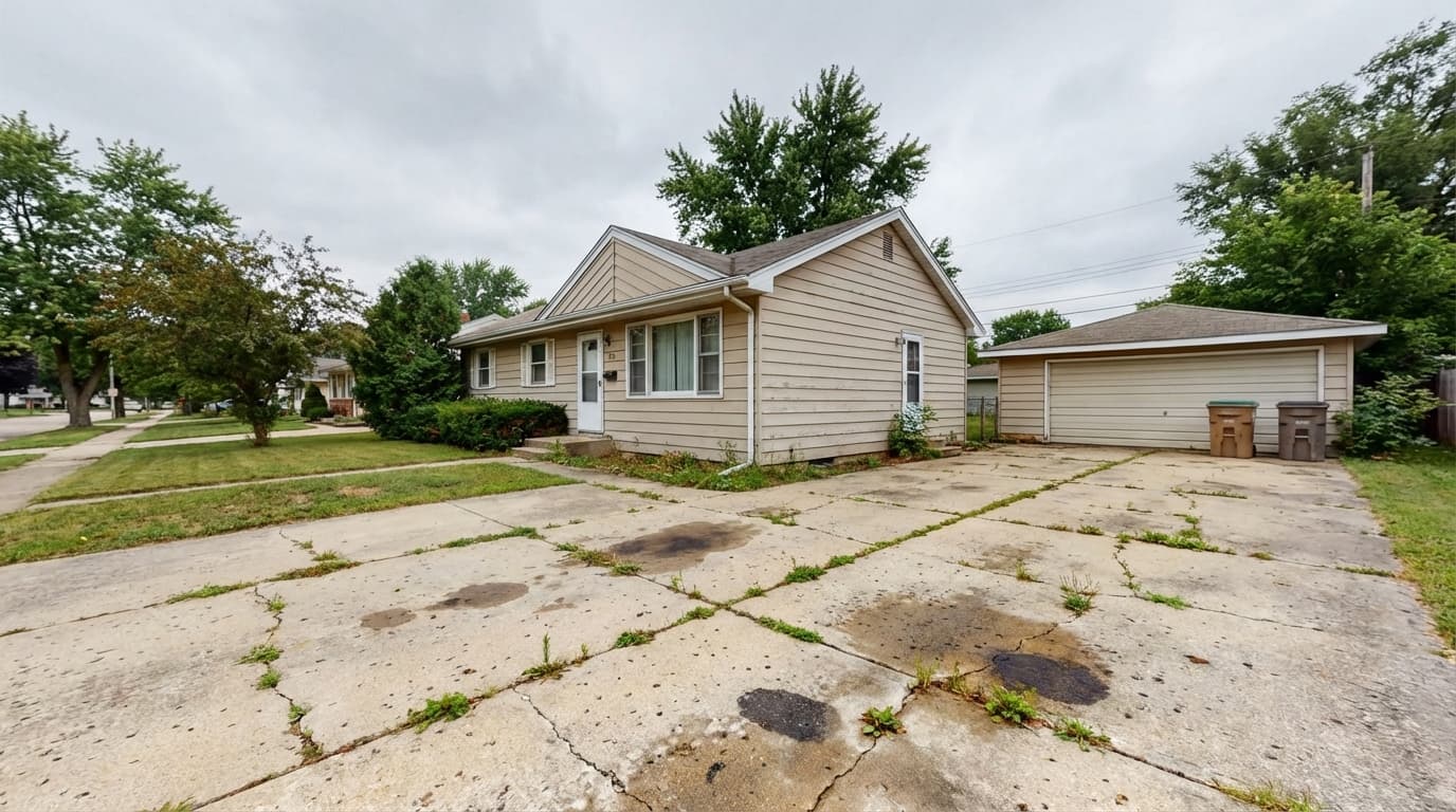 Cracked driveway in front of a suburban home before replacement